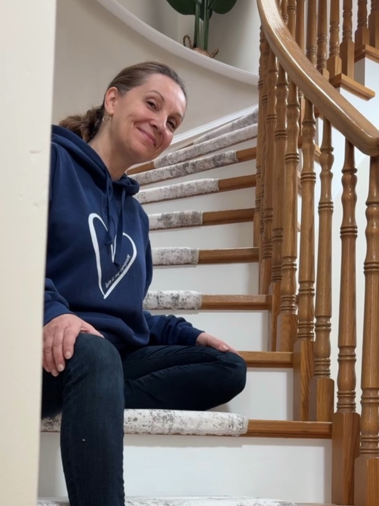 Monika sitting on a curved staircase with a freshly laid runner, smiling