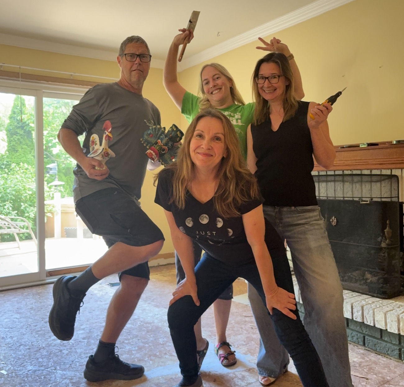The four of us in a stripped-out living room, mid-job and mid-joke: a paintbrush, a drill and a rooster figurine held aloft.